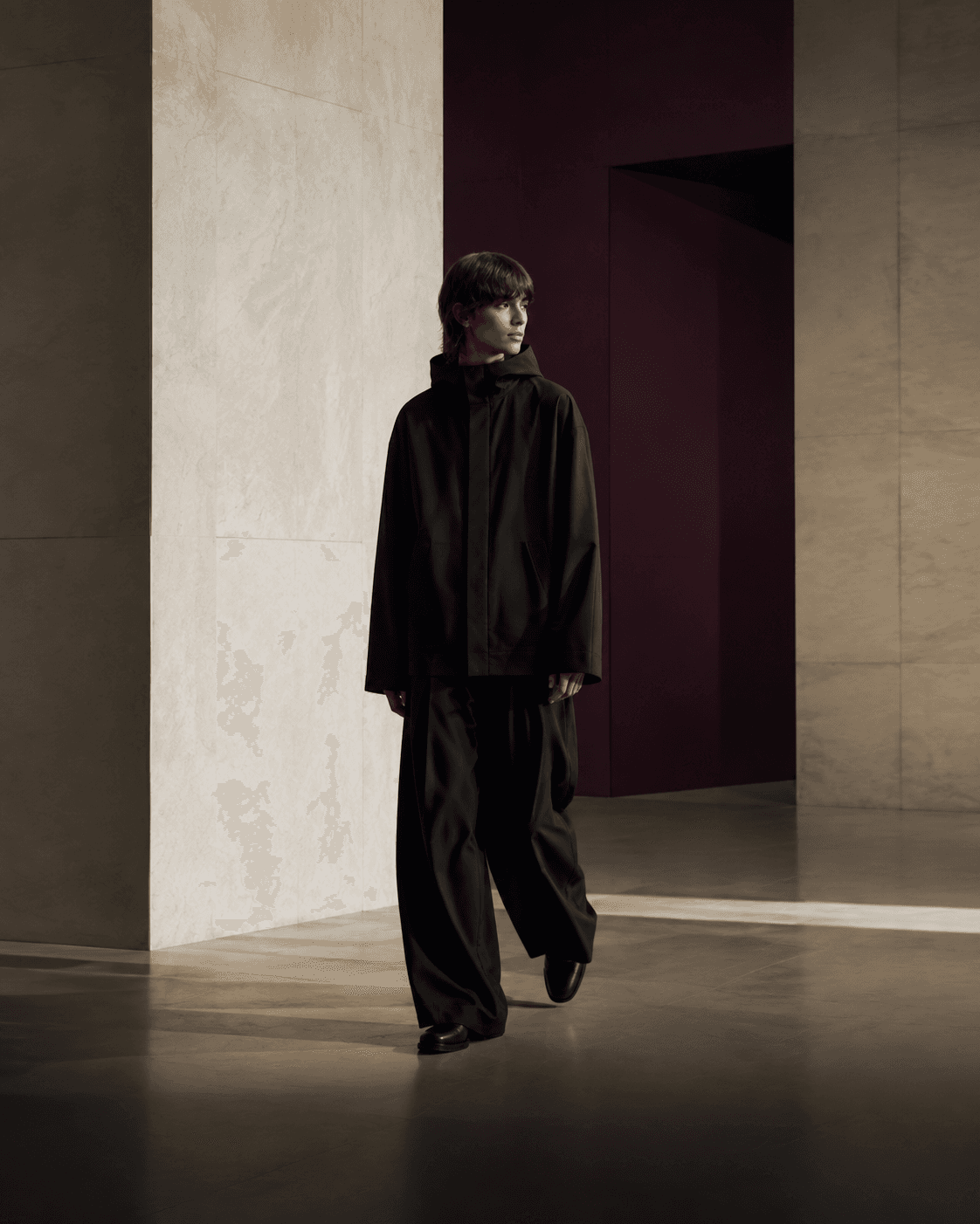 Full-length view of a model in an oversized ink silhouette within a modernist interior